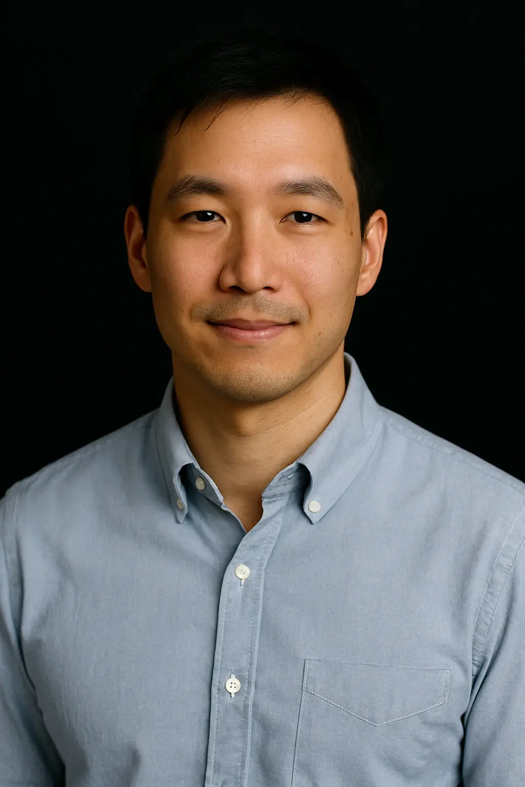 Professional headshot of a calm and approachable male Real Estate Marketing Specialist in a casual light blue shirt, ideal for team pages or company directories
